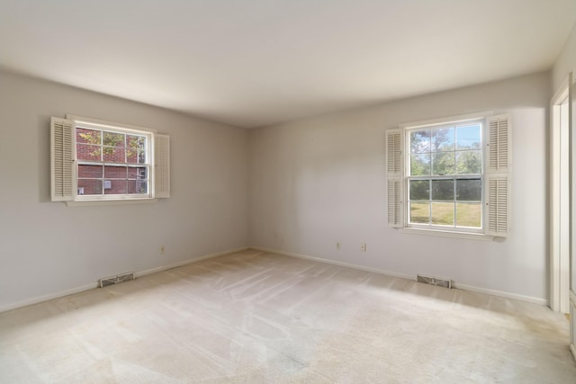 spare room with plenty of natural light, light colored carpet, and baseboards