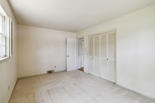 unfurnished bedroom with light carpet, a closet, and baseboards