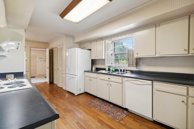 kitchen with white appliances, a sink, dark countertops, ornamental molding, and light wood-style floors