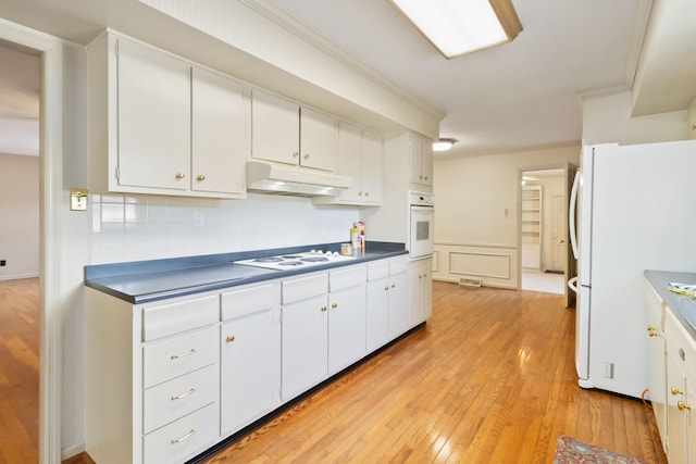 kitchen featuring white appliances, under cabinet range hood, white cabinets, light wood finished floors, and crown molding