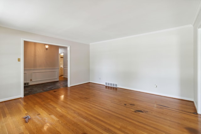 empty room featuring ornamental molding, wood finished floors, and baseboards