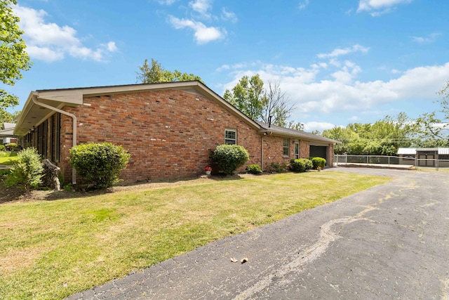 view of side of property featuring brick siding, an attached garage, and asphalt driveway