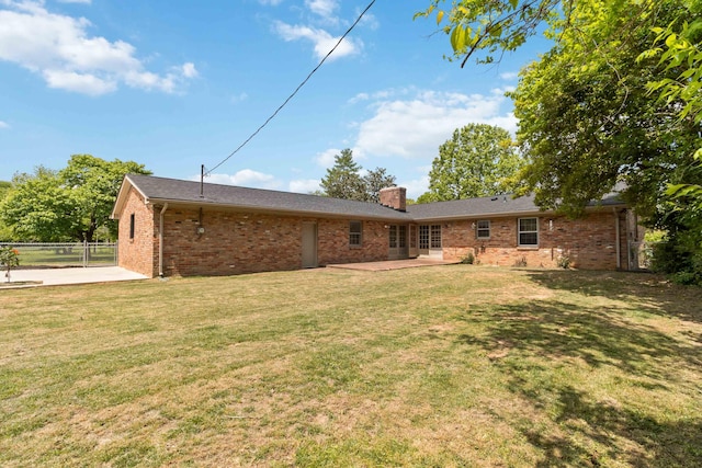 rear view of property with a patio area, brick siding, and a chimney
