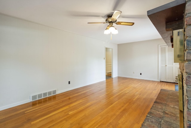 unfurnished living room featuring wood finished floors, ceiling fan, baseboards, and a fireplace
