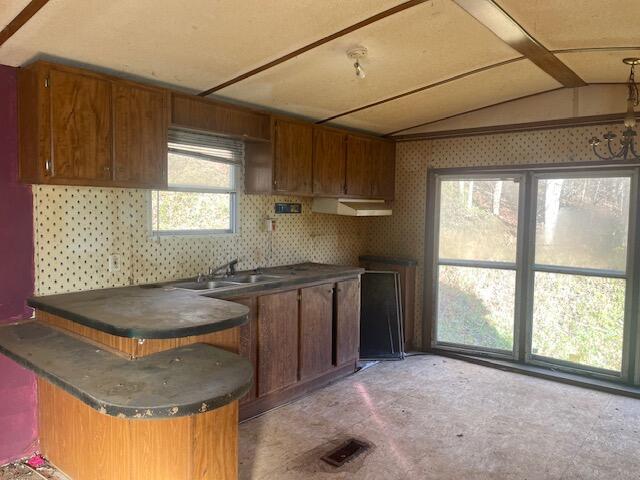 kitchen with lofted ceiling, a sink, brown cabinets, and dark countertops