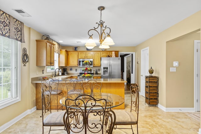 kitchen featuring stainless steel appliances, a sink, a peninsula, and baseboards