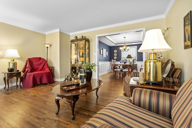 living room with wood finished floors, crown molding, a chandelier, and wainscoting