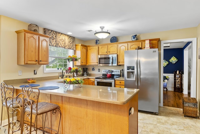 kitchen with stainless steel appliances, a peninsula, light countertops, and a breakfast bar area