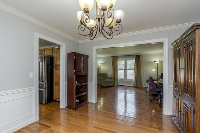 office space featuring a chandelier, ornamental molding, wood finished floors, and a wainscoted wall
