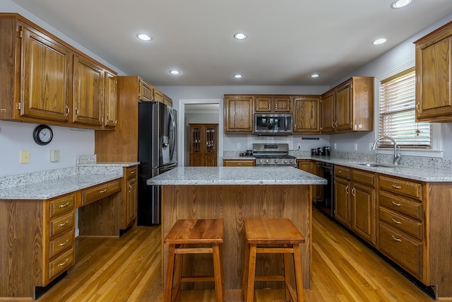 kitchen featuring black appliances, a sink, light wood-style flooring, a center island, and recessed lighting