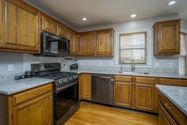 kitchen with dishwasher, range with gas stovetop, a sink, brown cabinets, and recessed lighting