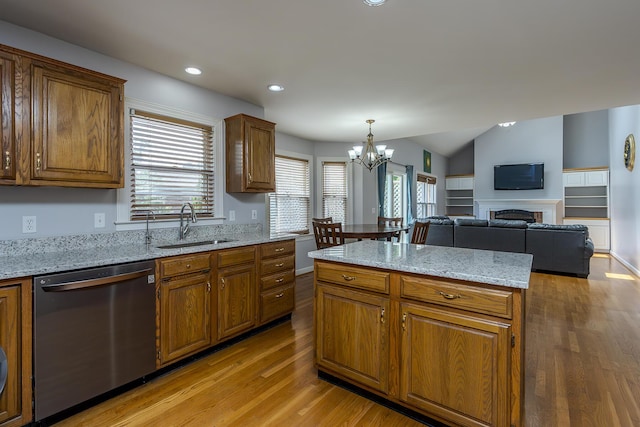 kitchen featuring dishwasher, a sink, light wood finished floors, brown cabinetry, and a fireplace