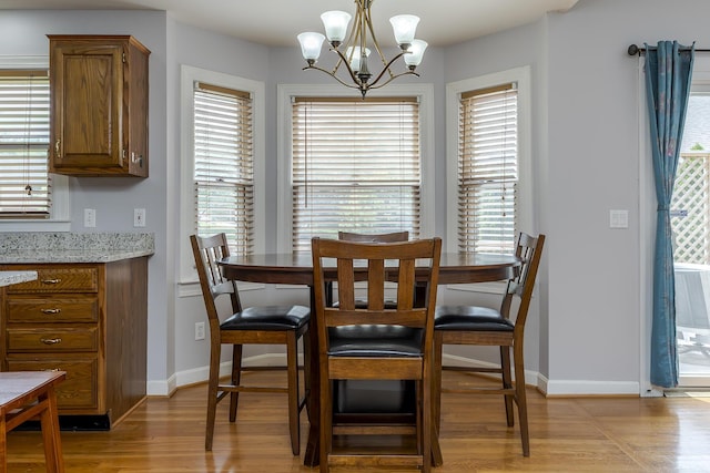 dining space featuring light wood-style flooring, a chandelier, and baseboards