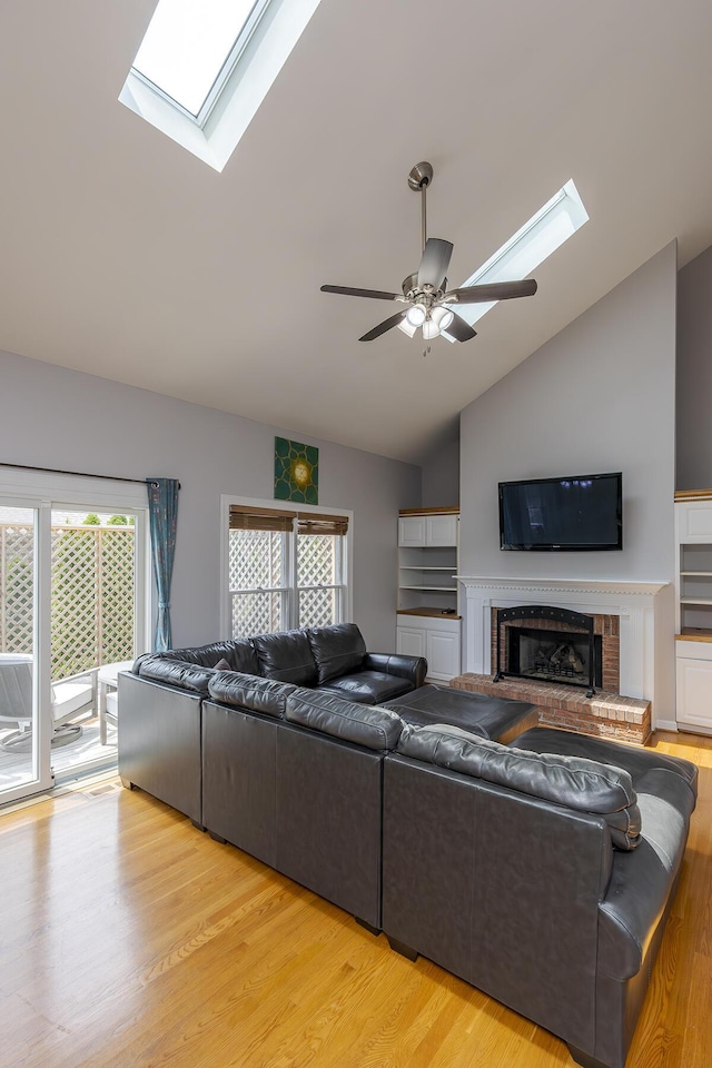 living area featuring a skylight, vaulted ceiling, plenty of natural light, a ceiling fan, and light wood finished floors