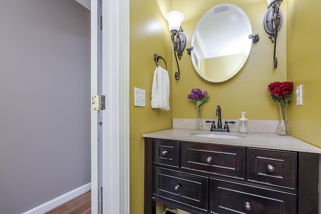 bathroom with vanity, wood finished floors, and baseboards