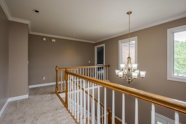 corridor featuring an upstairs landing, a chandelier, baseboards, carpet floors, and ornamental molding