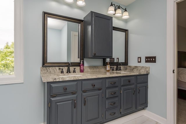 ensuite bathroom featuring double vanity and baseboards