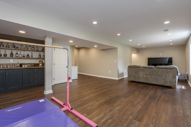 living room with dark wood finished floors, bar area, recessed lighting, and baseboards
