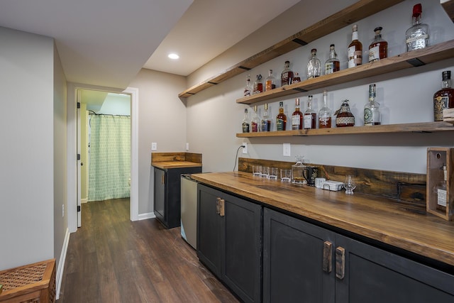 indoor wet bar with dark wood-style flooring, recessed lighting, and baseboards