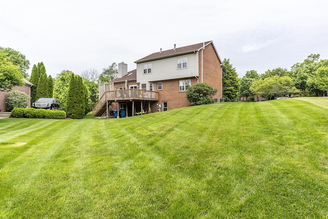 rear view of property with stairway, a wooden deck, a lawn, and brick siding