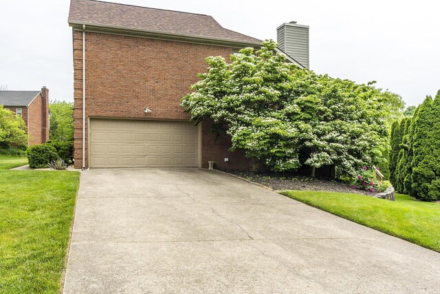 view of front of property with a garage, brick siding, driveway, and a front yard