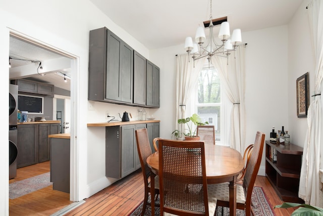 647 N Limestone, Lexington, KY 40508 - dining space with estacked washer and dryer, a chandelier, light wood-style flooring, and baseboards
