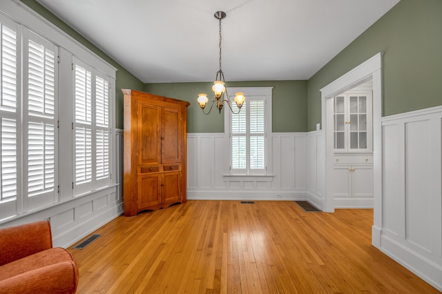 133 Victory Ave, Lexington, KY 40502 - unfurnished dining area with a chandelier, light wood-type flooring, a decorative wall, and wainscoting