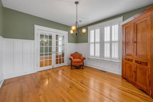 133 Victory Ave, Lexington, KY 40502 - unfurnished room featuring french doors, a wainscoted wall, a chandelier, light wood finished floors, and a decorative wall