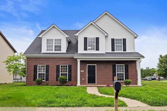 traditional home featuring brick siding, a front yard, and roof with shingles