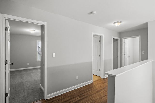 hall with an upstairs landing, baseboards, and dark wood-style flooring