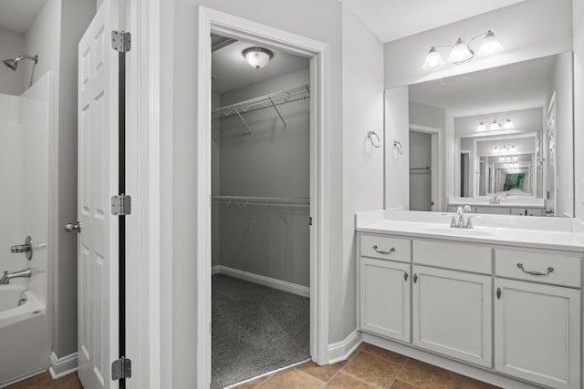 bathroom featuring vanity, a spacious closet, bathtub / shower combination, and baseboards