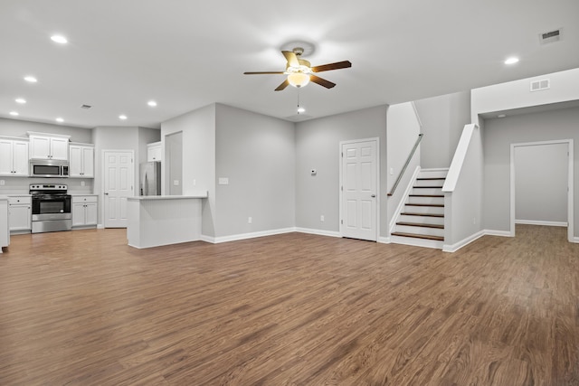 unfurnished living room featuring ceiling fan, wood finished floors, recessed lighting, stairway, and baseboards