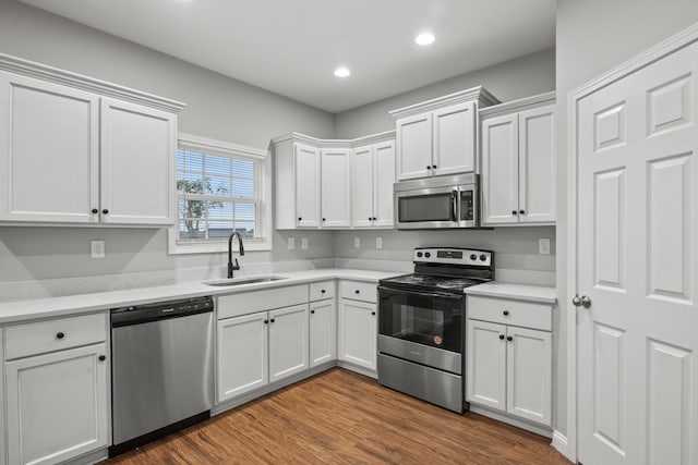 kitchen with stainless steel appliances, a sink, light countertops, recessed lighting, and dark wood-style floors