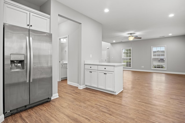kitchen featuring stainless steel fridge with ice dispenser, ceiling fan, light wood finished floors, white cabinets, and baseboards