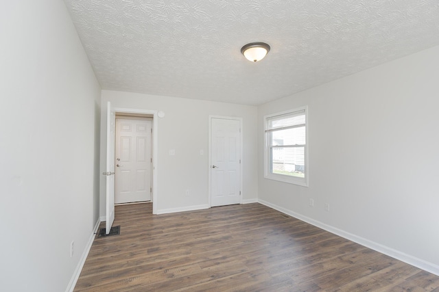 unfurnished bedroom with dark wood-type flooring, a textured ceiling, and baseboards