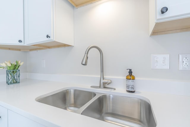 kitchen view of a sink, white cabinets, and light countertops
