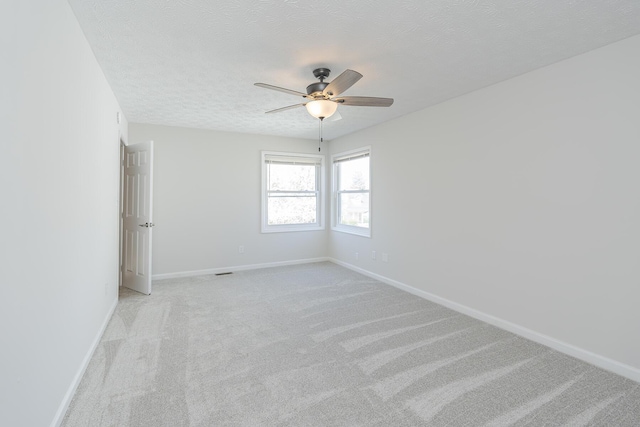 empty room with ceiling fan, baseboards, light colored carpet, and a textured ceiling