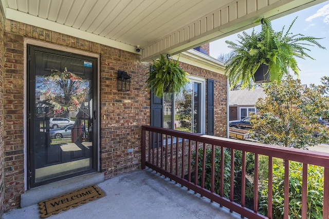 view of exterior entry featuring brick siding and covered porch