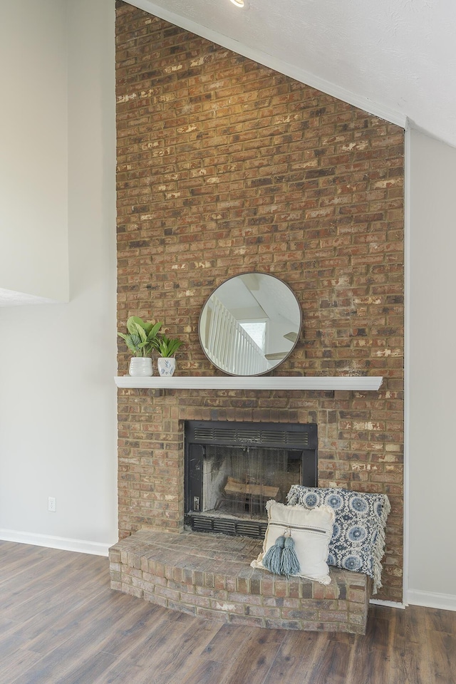 detailed view of a brick fireplace, wood finished floors, and baseboards