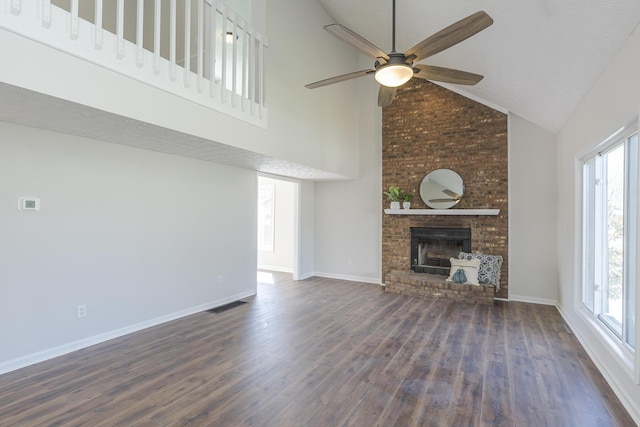 unfurnished living room featuring a fireplace, wood finished floors, healthy amount of natural light, high vaulted ceiling, and ceiling fan