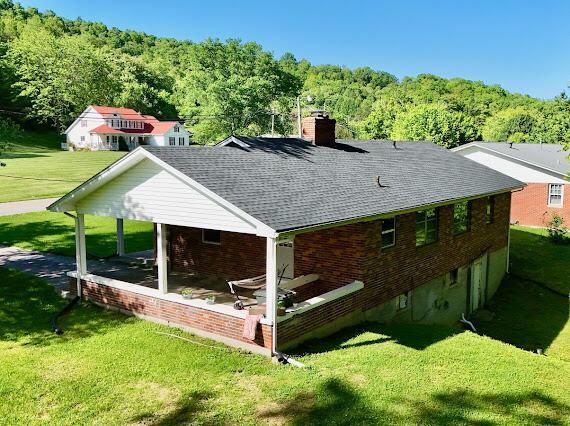 4216 N Ky 11, Cannon, KY 40923 - back of property featuring a chimney, a wooded view, a lawn, roof with shingles, and a patio