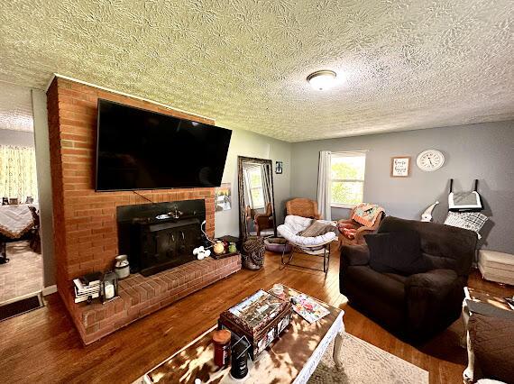 4216 N Ky 11, Cannon, KY 40923 - living area featuring wood finished floors, a textured ceiling, and a brick fireplace