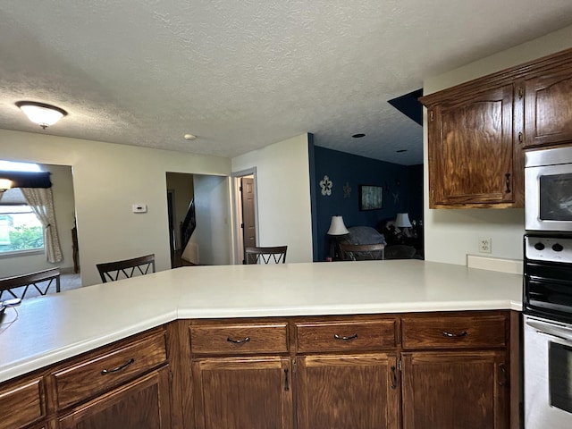 296 Ferry Rd, Somerset, KY 42503 - kitchen with stainless steel microwave, light countertops, a peninsula, double oven, and a textured ceiling