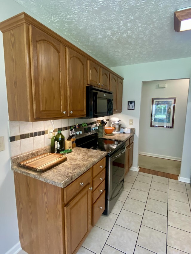 45 Rons Pond Rd, Corbin, KY 40701 - kitchen with electric range, black microwave, light tile patterned floors, decorative backsplash, and brown cabinets