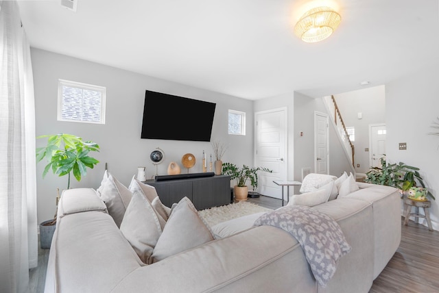 living area featuring healthy amount of natural light, wood finished floors, and stairs
