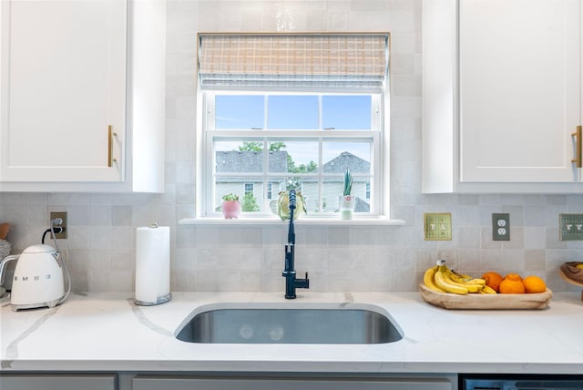 kitchen featuring a sink, white cabinets, backsplash, dishwasher, and light stone countertops