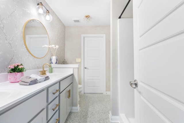 bathroom with toilet, double vanity, tile patterned floors, and baseboards