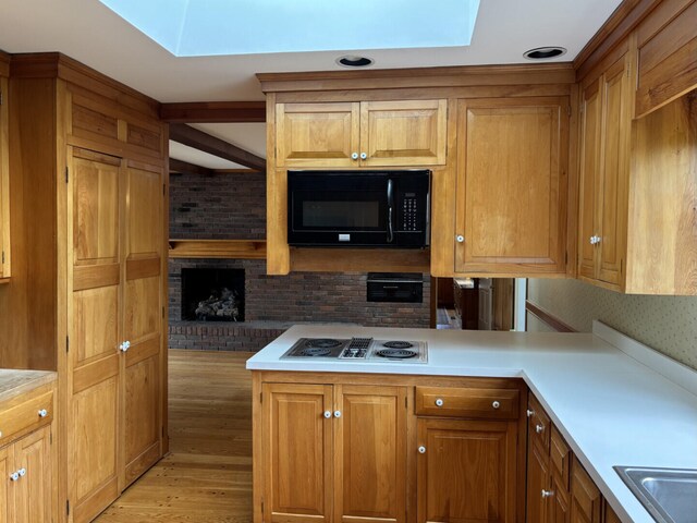 1439 Stanford St, Lancaster, KY 40444 - kitchen featuring black microwave, a skylight, stovetop with downdraft, light wood-style floors, and light countertops