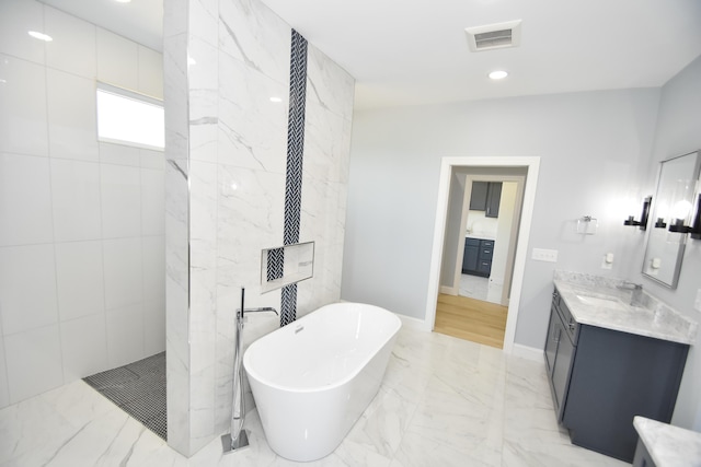 full bathroom with marble finish floors, a freestanding tub, vanity, walk in shower, and recessed lighting
