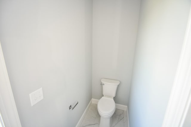 bathroom featuring marble look tiles, toilet, and baseboards